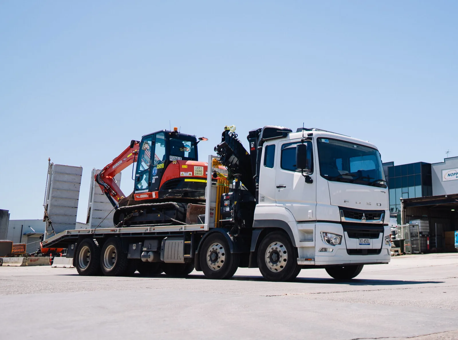 A truck transporting heavy construction equipment, emphasizing logistics and safety at work zones.