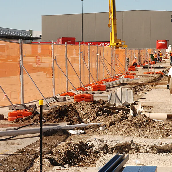 Safety fencing with braces and netting surrounding a construction worksite to prevent debris and unauthorized access.