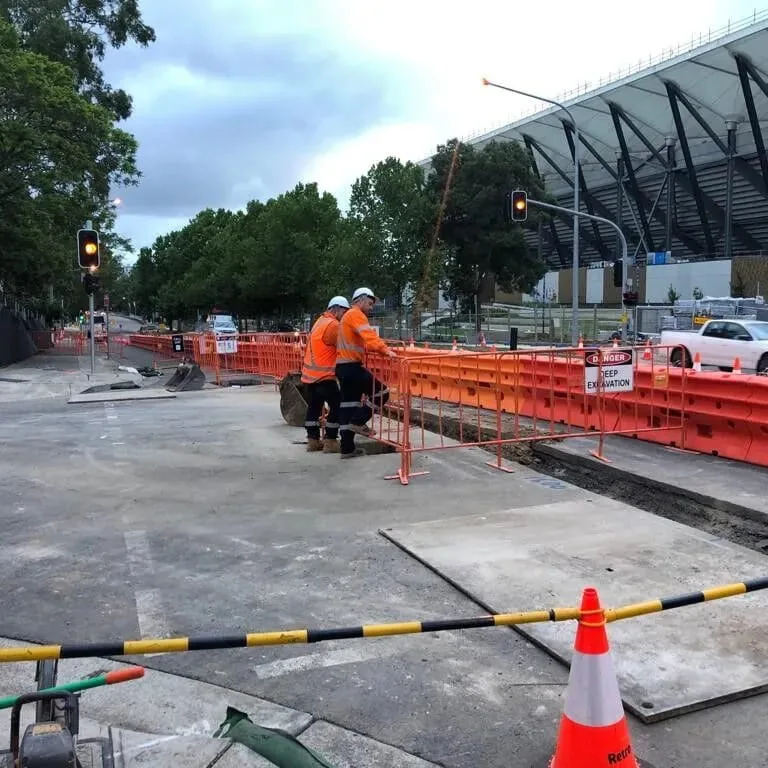 Safety barriers and fencing installed along a light rail track to protect pedestrians and secure the construction area.