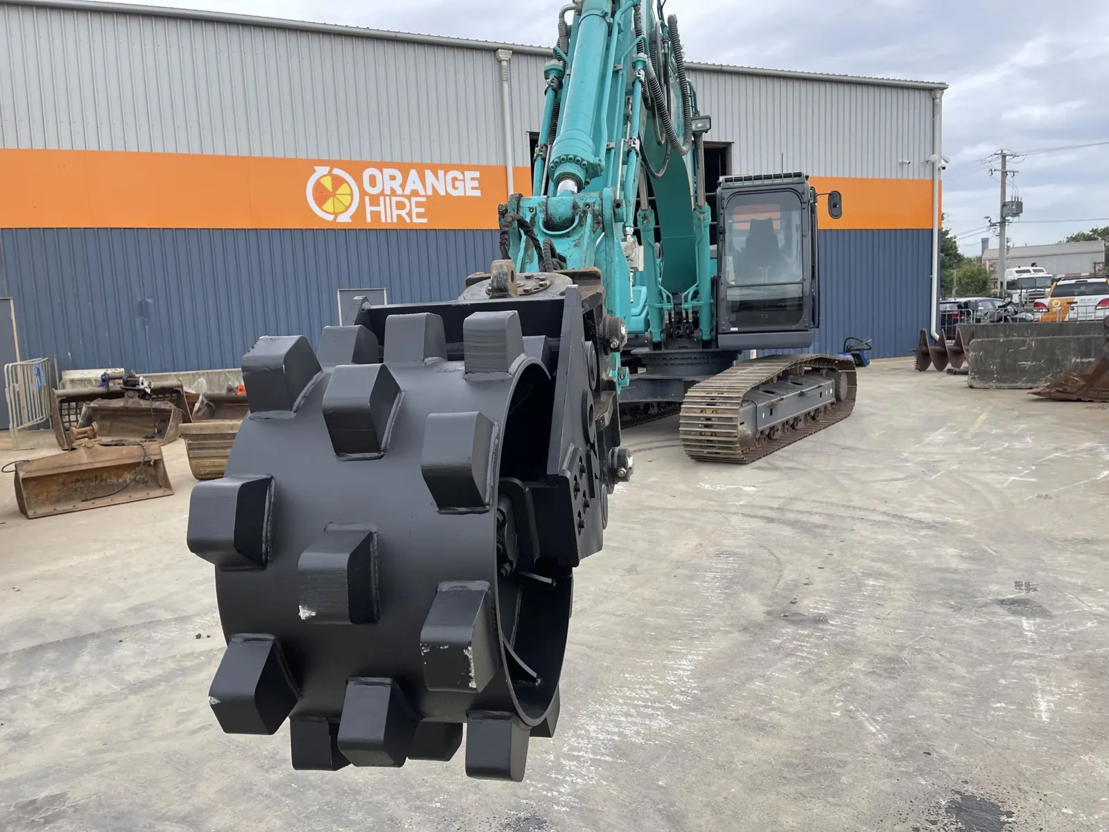 Compaction wheel attached to construction equipment, used for securing soil around newly installed safety barriers.