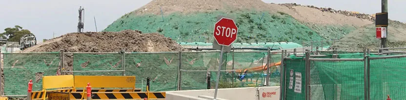 Various dependable construction equipment positioned along a roadway, supporting barrier installation and roadwork operations.