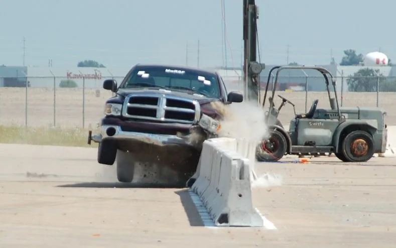 Workers installing safety barriers on a road construction site to prevent vehicle collisions.