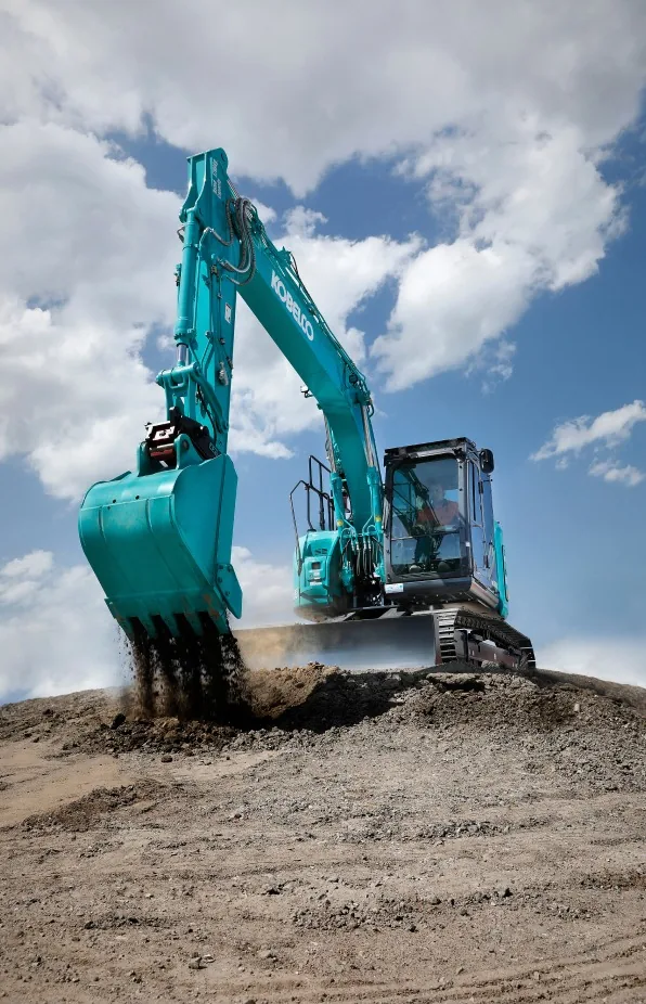 A man operating heavy equipment to dig and move sand at a construction site, focusing on earthmoving tasks.