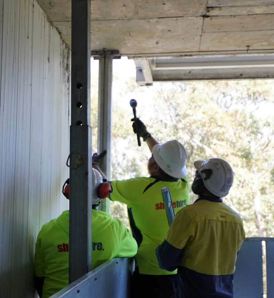 Workers positioning props to provide temporary structural support during an active construction project.