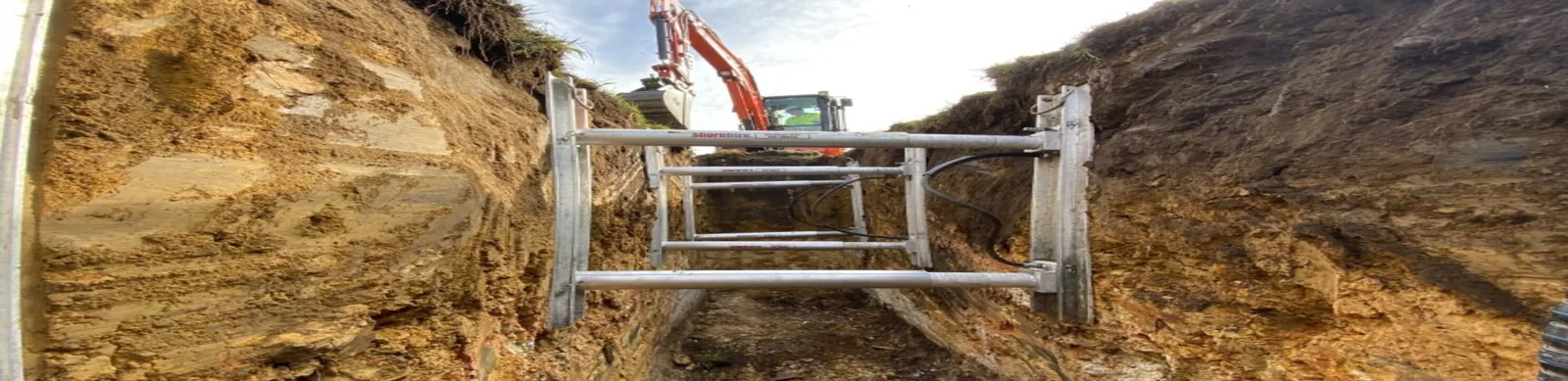 Workers installing structural braces in an underground excavation site to support trench walls and ensure safety during construction.