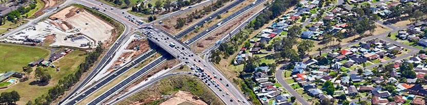 Overhead view of roads, houses, and railway tracks, highlighting infrastructure development and urban planning.