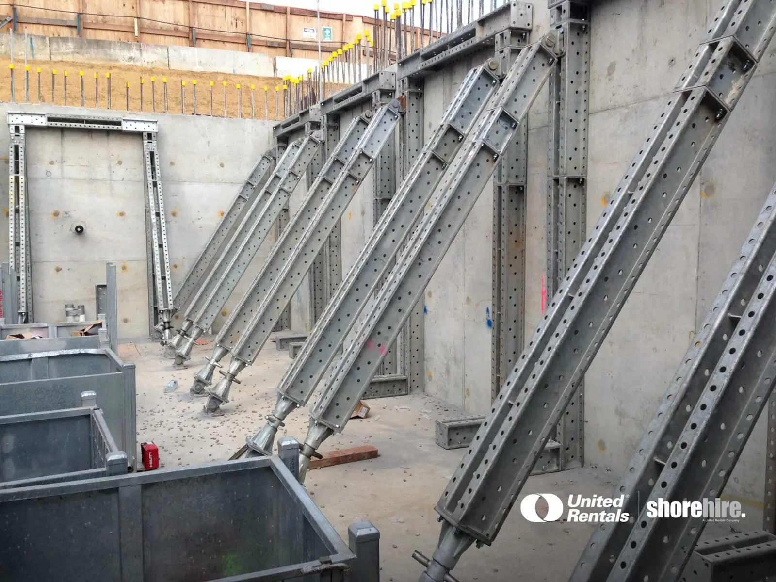 Modular Props are anchored to a concrete retaining wall, providing temporary structural support during construction.